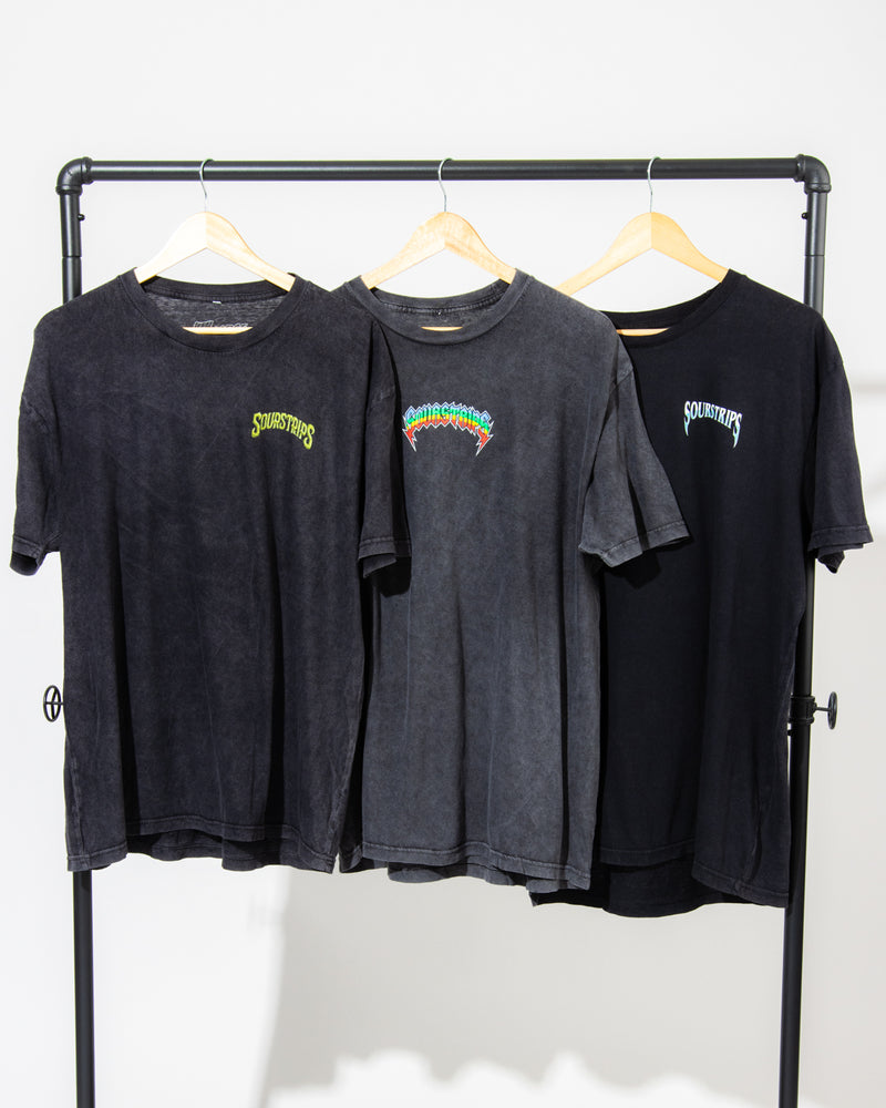 Three black SourStrips Sour Storm Tees with unique graphics hang on wooden hangers from a black rack, showcasing the perfect unisex cotton style against a crisp white background.