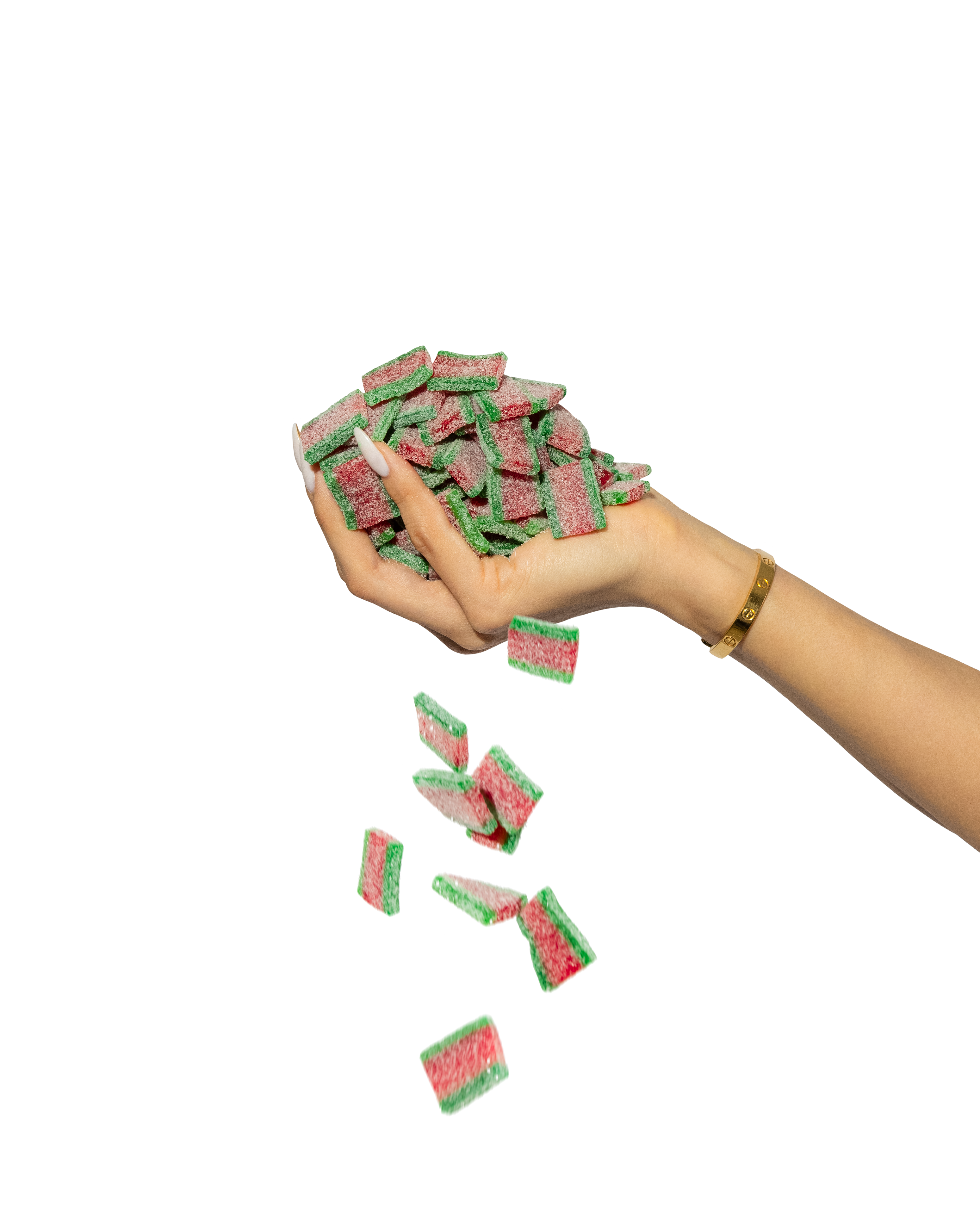 A hand wearing a gold bracelet drops several rectangular Sour Strips Bites-Four Pack candies by Sour Strips, featuring rainbow flavors with green, red, and white layers, against a black background.